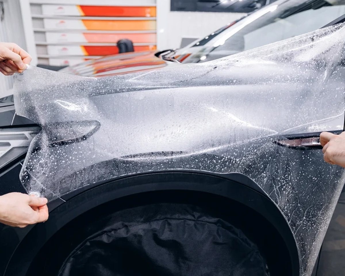 Clear paint protection film being laid over a car's front wing